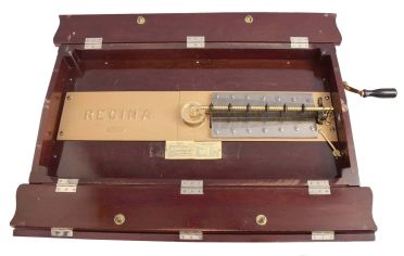American, Regina Music Box Co., Style No. 6 Orchestral 27" Folding Top Table Model music box also sometimes called the "Casket Model". Mahogany case with applied carving and shaped bracket feet. Interior with original Regina Company celluloid label, the serial number stamped into the cast iron bedplate = 31207, and an 11" double comb mechanism, with removable crank. Includes 23 discs