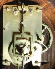 Patent Timepiece or "Banjo" Clock, Concord, Massachusetts, the mahogany veneered, gilded rope molded case with acorn finial over the zinc roman numeral dial, original reverse-painted glasses, the lower depicting "Aurora" on her festooned chariot driven by two winged horses set before a gleaming sunrise and framed within a geometric border, the waist glass flanked by brass side ornaments in gold, green and red frames gilt scroll work within a gilt border, below is a gilded pedestal with fluted acorn drop and eight balls, eight day brass movement with alternate train layout, cut-outs on front and back plates, and recoil escapement and regulated by a brass-faced lead backed pendulum bob and iron rod.