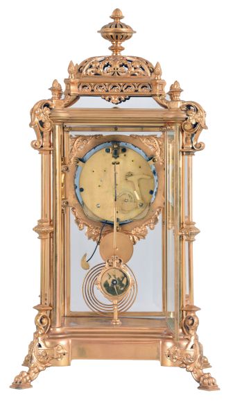 Ansonia Clock Co., New York, "Excelsior" crystal regulator, 8 day, time and strike, spring driven movement with visible Brocot escapement in a gilt finished brass case on claw feet, cream porcelain dial with Roman numerals and red interstitial decorations, cast pendulum with female face, strikes on cathedral gong.