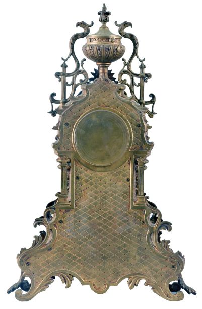 France, Mantel Clock with porcelain roman numeral dial and decorative cast center, blued-steel hands, complicated classical-styled cast brass case with urn finial at the top flanked by griffins, a female goddess of the sun life mask surmounting the dial, four fluted columns supporting the whole and a leaf and scroll base with cross hatching and four scroll-leafed feet, round brass French eight day movement with rack hour striking on a gong and pendulum.