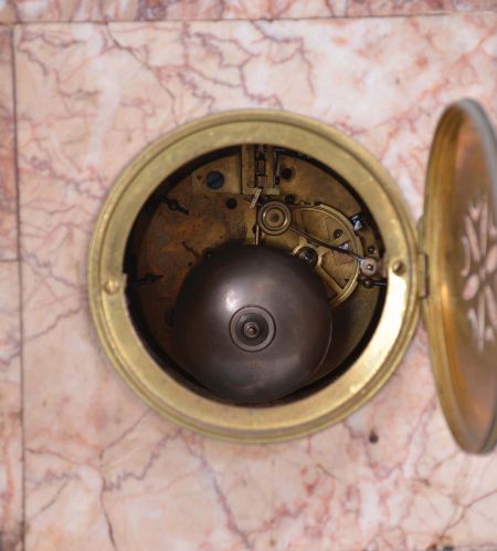 France, Variegated Pink Marble Figural Clock Garniture, the clock with off-white arabic numeral dial within a brass bezel and beveled glass set within the marble case with scroll work dial surround, on raised feet and and plinth for the statue titled "La Cigale" a sculpture first presented by Sylvain Kinsburger, the patinated figure of a young maiden no doubt playing the 