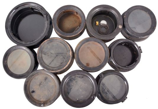 18 (Eighteen) Marine Clock Cases: black painted wood and brass, black phenolic, and nickel-plated brass marine clock cases by various makers in assorted sizes. A number of nickel plated wall mounting plates are also included.