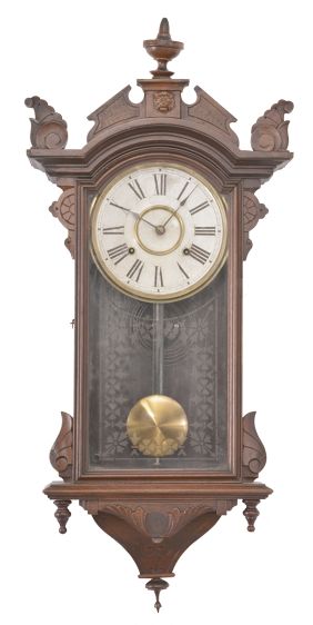 Clocks- 2 (Two): (1) E. N. Welch, Forestville, Conn., wall clock, 8 day, time only, spring driven movement in an ash case with walnut burl accent and painted metal dial, c1890; (2) E. N. Welch, Forestville, Conn., wall clock, 8 day, time and strike, spring driven movement in a walnut case with carved elements, c1880.