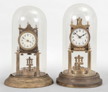 Clocks- 2 (Two) 400 day clocks: (1) Uhrenfabrik Urania Ltd., Germany, 400-day mantel clock, time only, spring driven movement with torsion disc pendulum, porcelain dial signed "Urania", under glass dome, c1908; (2) Gustav Becker, Freiberg, Germany, 400-day mantel clock, time only, spring driven movement with torsion disc pendulum, white enamel dial signed "K.C. Co. Germany", c1912.
