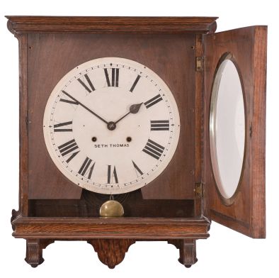Clocks- 2 (Two): (1) Ansonia Clock Co., New York, "Gresham" wall hanging gallery clock with a 12 inch dial, dial reading "P. Allana & Bros / Karachi." and a spring driven 8 day time and strike movement in a finished mahogany case. c1894. (2) Seth Thomas Clock Co., Thomaston, Conn., "Office No. 5" wall hanging clock with a spring driven 8 day time and strike movement in an oak case. c1904.