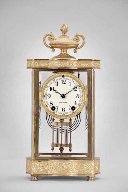 Seth Thomas Clock Co., Thomaston, Conn., "Empire No. 7" crystal regulator, 8 day, time and strike, spring driven movement in a glazed gilt brass case with urn finial, cream porcelain dial and blued steel hands.
